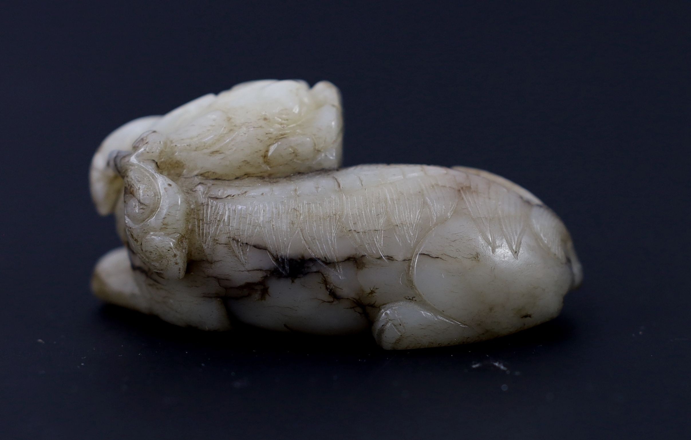 A Chinese Ming white and black jade figure of a recumbent beast, 6.8 cm long